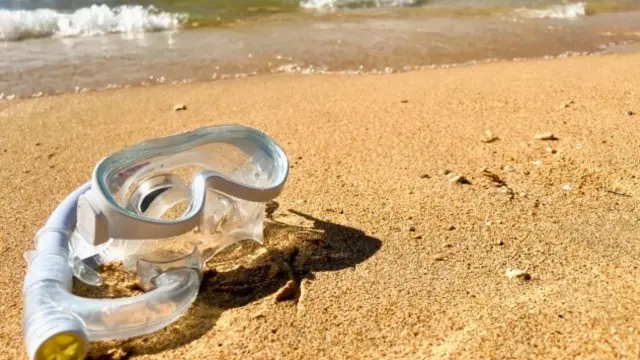 砂浜に置いてあるシュノーケリングの水中メガネ